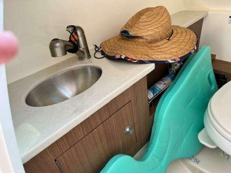 2018 Boston Whaler 270 Vantage bathroom sink and storage area with straw hat.