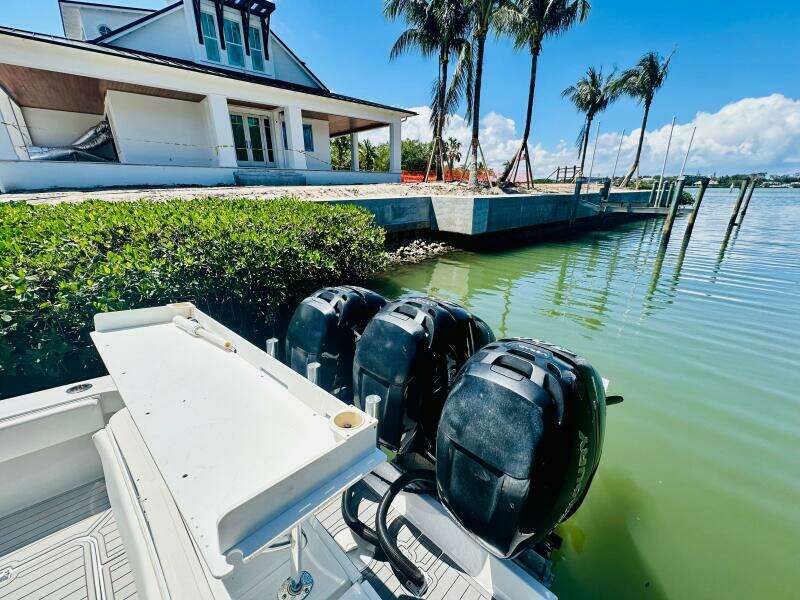 2000 Luhrs Tournament 320 Open boat docked near waterfront house with palm trees.