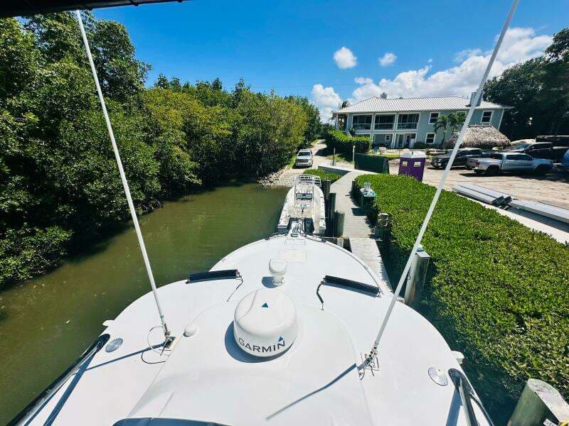 2000 Luhrs Tournament 320 Open boat docked near a canal with lush greenery.