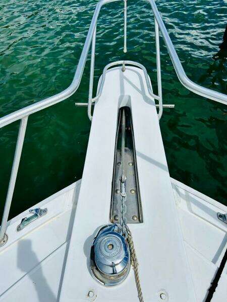 1988 Bertram 54' yacht bow with anchor chain and winch over green water.