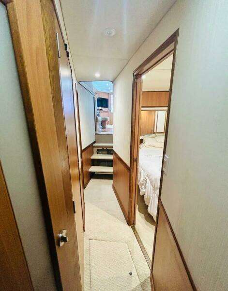 1988 Bertram 54' yacht interior hallway with wood paneling and bedroom view.