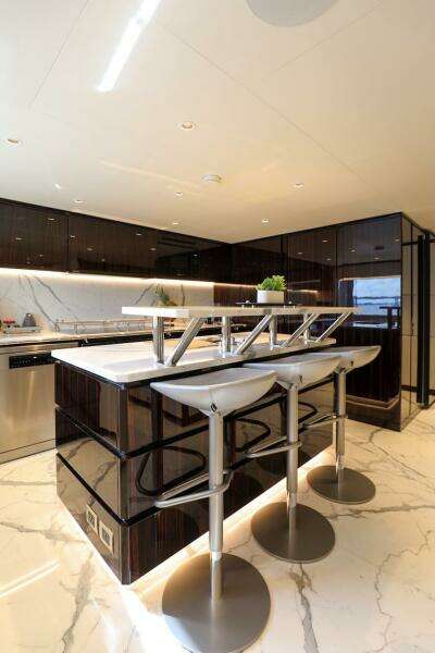 Luxurious 2025 Majesty 120 yacht kitchen with modern bar stools and sleek marble flooring.