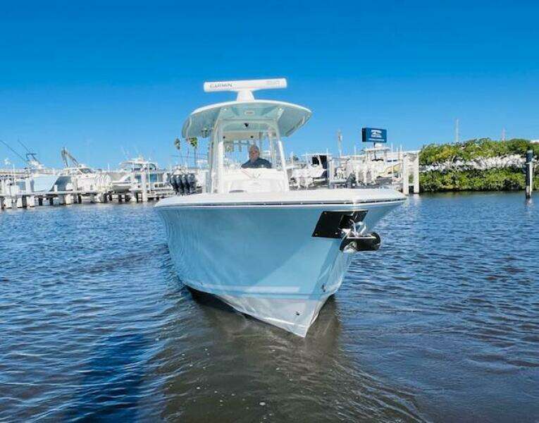 2021 Cobia 301 Center Console boat on water near marina under clear blue sky.