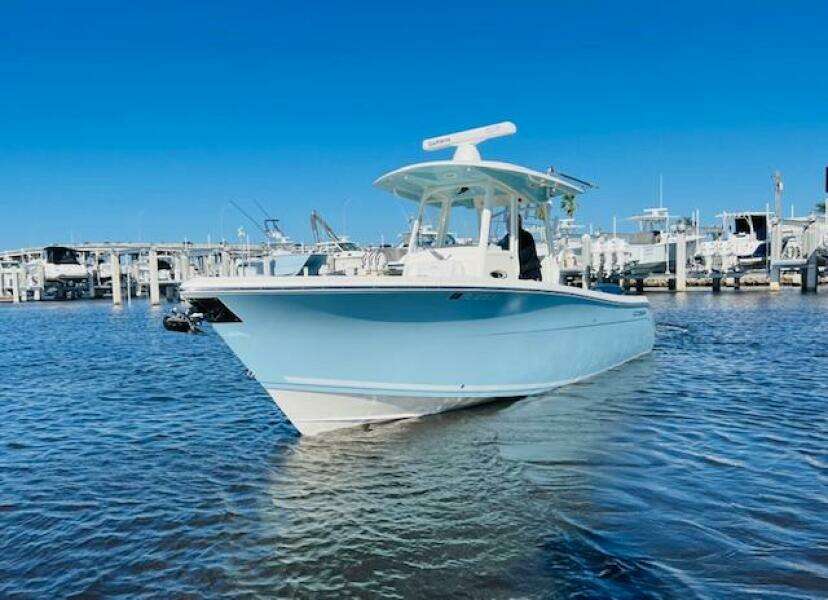2021 Cobia 301 Center Console boat docked in marina under clear blue sky.