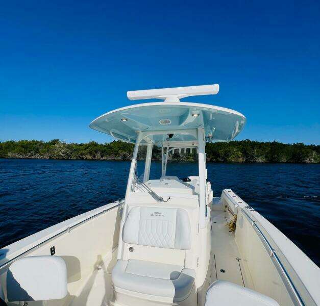 2021 Cobia 301 Center Console boat on calm water under clear blue sky.