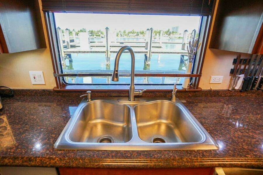 Stainless steel double sink on granite countertop with marina view through window.