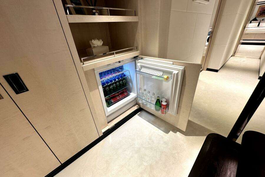 Mini fridge in 2023 Majesty 120 yacht, stocked with beverages, open in luxurious interior.
