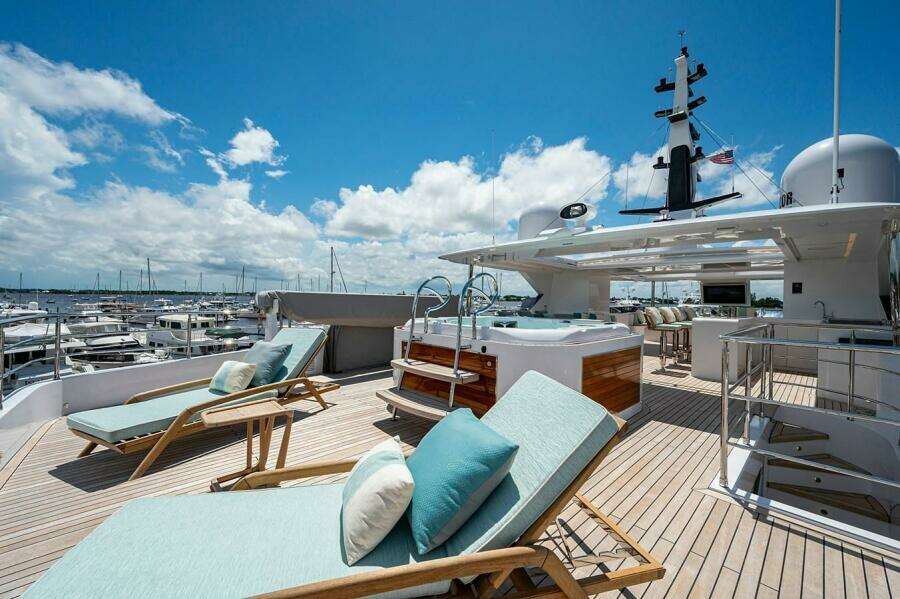 Luxurious 2020 Majesty 140 yacht deck with sun loungers and jacuzzi under blue sky.