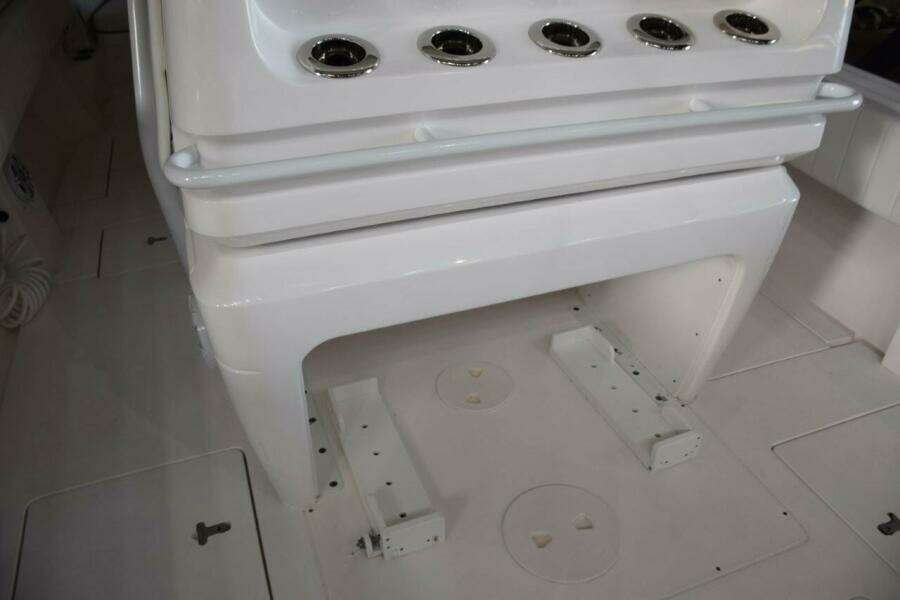 Behind Helm Seat Console, Drink Holder Or Rod Holders And Safety Grab Railing, Cooler Chocks Beneath.